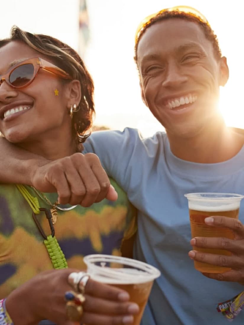 Casal sorrindo com cerveja ao sol